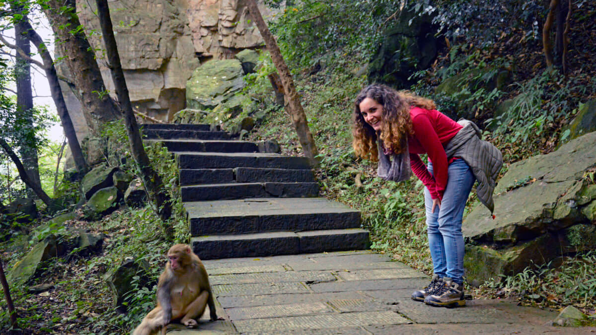 Blogger posing with a macaque on the hiking trail in Zhangjiajie, China.